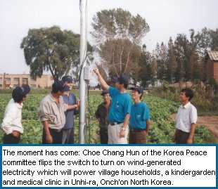Choe Chang Hun of the Korea Peace committee flips the switch to turn on wind-generated electricity